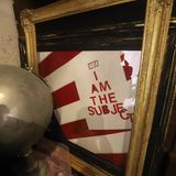 Ein Kunstwerk, das anscheinend eine US-Flagge sowie ein Papier mit dem Satz "I am the subject" ("Ich bin das Subjekt") beinhaltet. Was das wohl bedeuten soll?