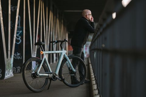 Ein Vanmoof S6 steht mit einem Mann auf einer Brücke