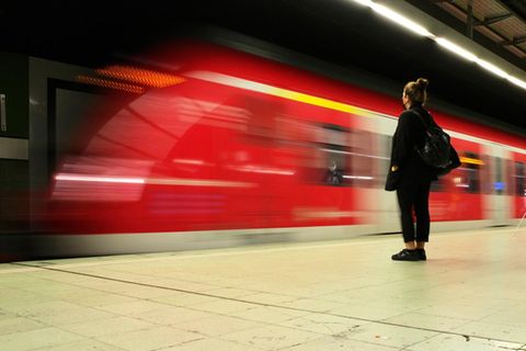 Pendlerpauschale Symbolbild: Frau steht am Bahnhof und eine S-Bahn fährt ein