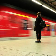 Pendlerpauschale Symbolbild: Frau steht am Bahnhof und eine S-Bahn fährt ein