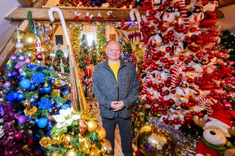 Thomas Jeromin steht inmitten von Weihnachtsbäumen in seinem Haus im Landkreis Schaumburg. Foto: Julian Stratenschulte/dpa