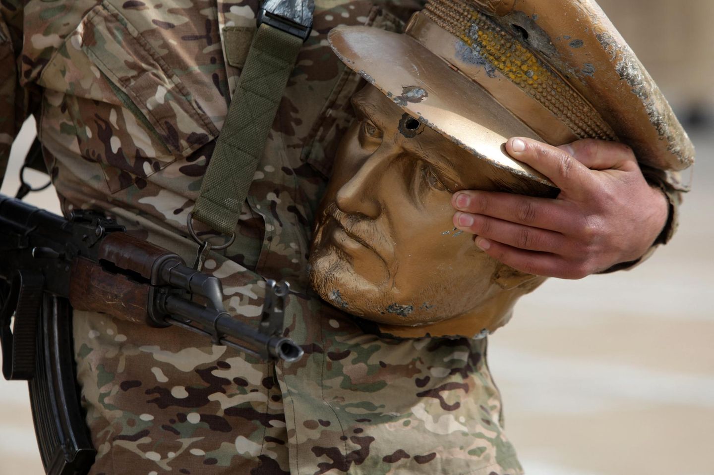 Ein Soldat hält ein abgeschlagenen Kopf einer Statue in der Hand
