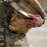 Ein Soldat hält ein abgeschlagenen Kopf einer Statue in der Hand