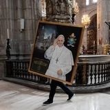 Eine Person trägt ein Gemälde von Papst Franziskus