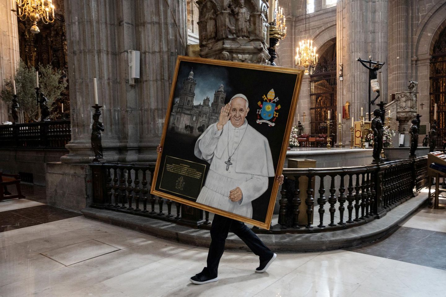 Eine Person trägt ein Gemälde von Papst Franziskus