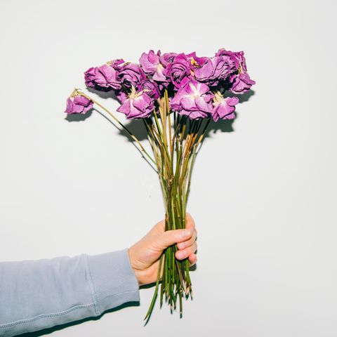 Person hält vertrockneten Blumenstrauß in der Hand
