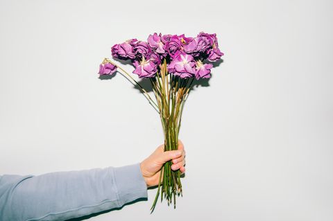 Person hält vertrockneten Blumenstrauß in der Hand