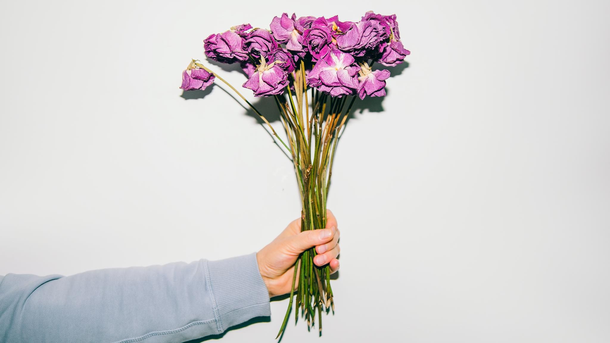 Person hält vertrockneten Blumenstrauß in der Hand