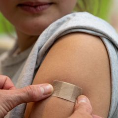 Symbolbild Corona-Impfung: Eine Ärztin klebt nach einer Impfung ein Pflaster auf den Arm einer Frau