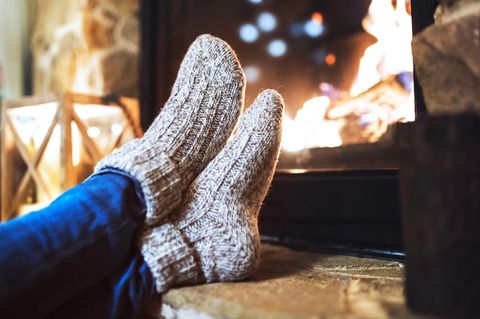 Deal News: Eine Frau sitzt mit Thermosocken vor dem Kamin