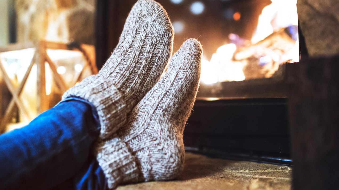 Deal News: Eine Frau sitzt mit Thermosocken vor dem Kamin