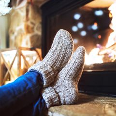 Deal News: Eine Frau sitzt mit Thermosocken vor dem Kamin