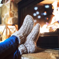 Deal News: Eine Frau sitzt mit Thermosocken vor dem Kamin