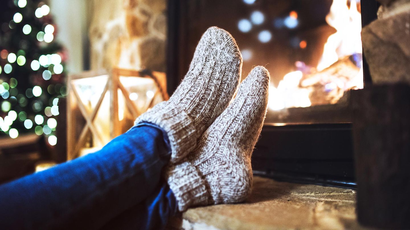 Deal News: Eine Frau sitzt mit Thermosocken vor dem Kamin