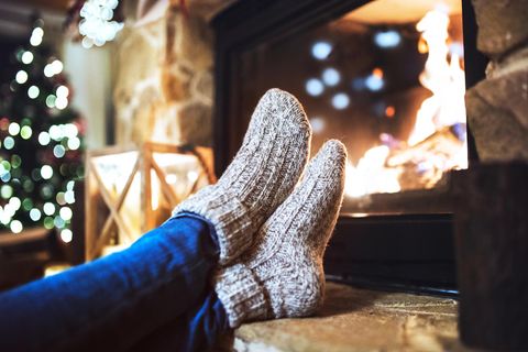 Deal News: Eine Frau sitzt mit Thermosocken vor dem Kamin