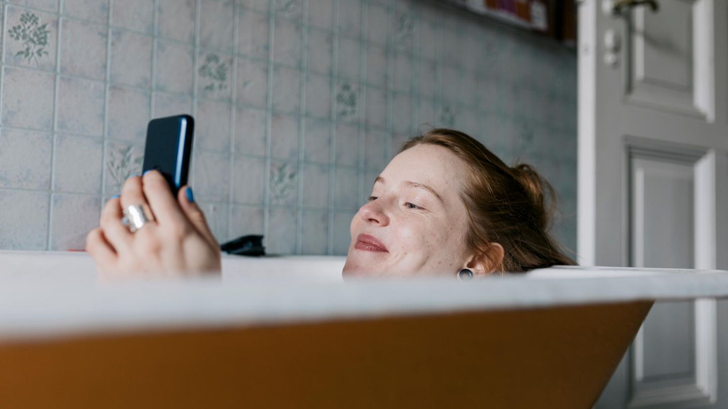 Frau in einer Badewanne am Handy