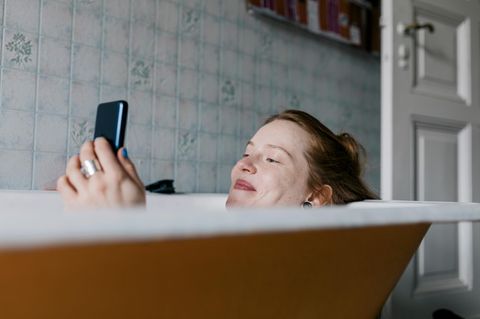 Frau in einer Badewanne am Handy