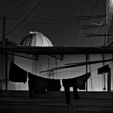 Der Blick über die Dächer einer Stadt Indiens. Im Vordergrund hängen Wäscheleinen, während dahinter ein Observatorium rausguckt