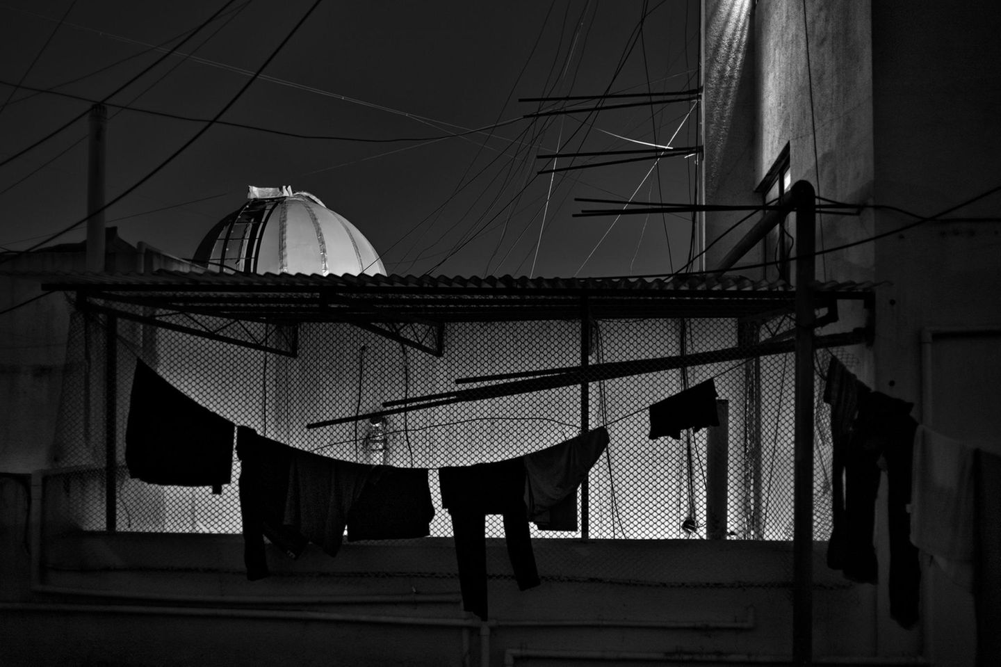 Der Blick über die Dächer einer Stadt Indiens. Im Vordergrund hängen Wäscheleinen, während dahinter ein Observatorium rausguckt