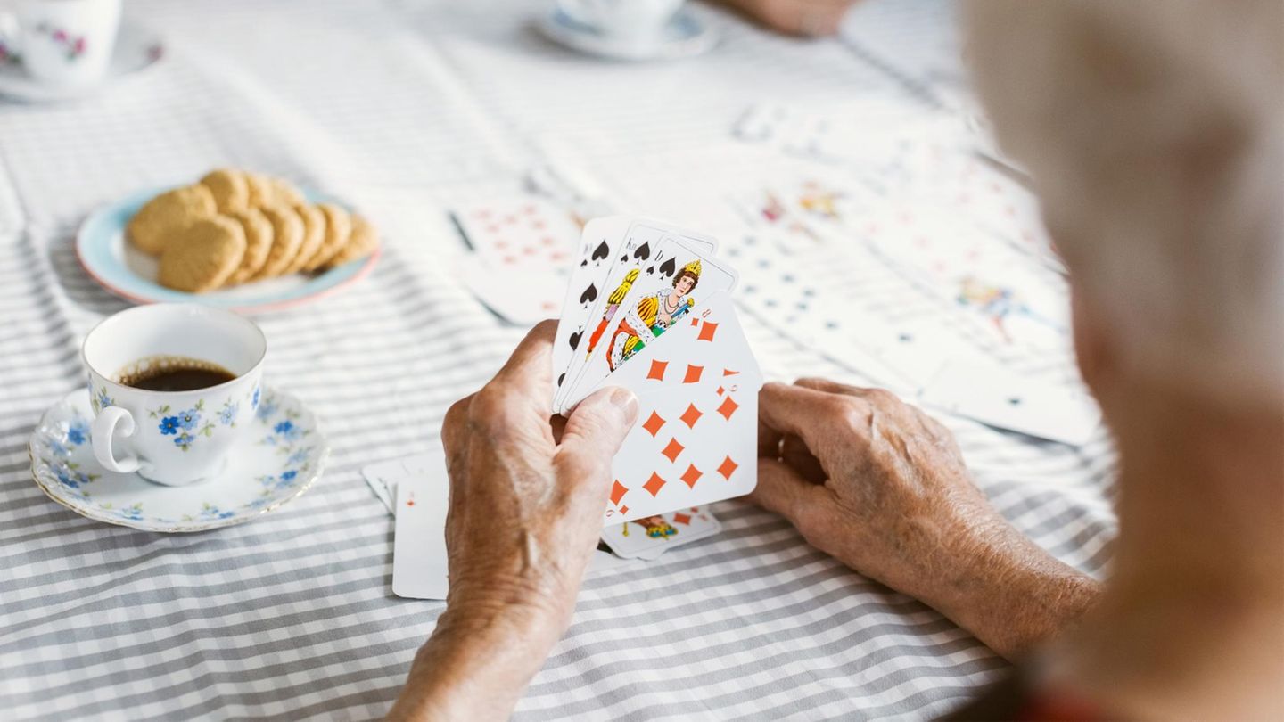Hände einer älteren Frau beim Kartenspielen im Pflegeheim
