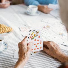 Hände einer älteren Frau beim Kartenspielen im Pflegeheim