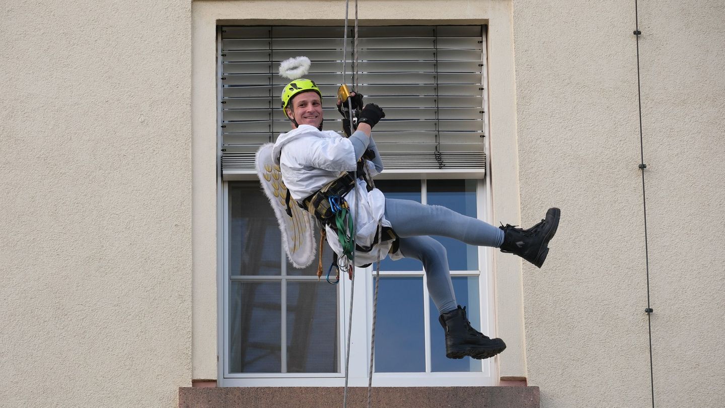 Ein Kamerad der Höhenrettung der Chemnitzer Feuerwehr seilt sich im Weihnachtsengel-Kostüm an der Fassade des Klinikums Chemnitz