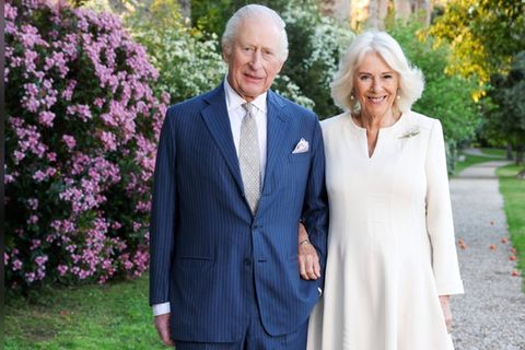 König Charles und Königin Camilla grüßen von der Weihnachtskarte in frühlingshafter Umgebung.