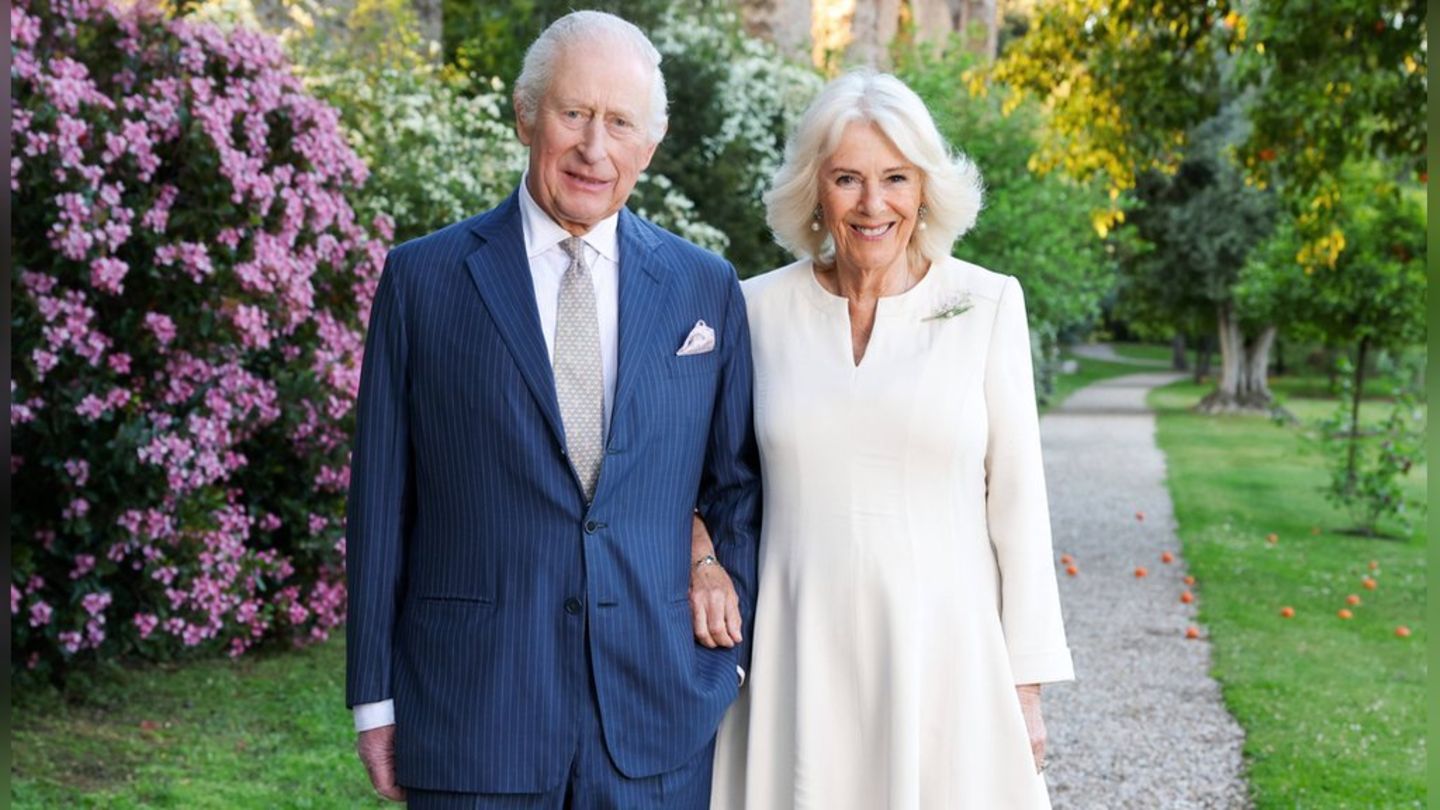 König Charles und Königin Camilla grüßen von der Weihnachtskarte in frühlingshafter Umgebung.