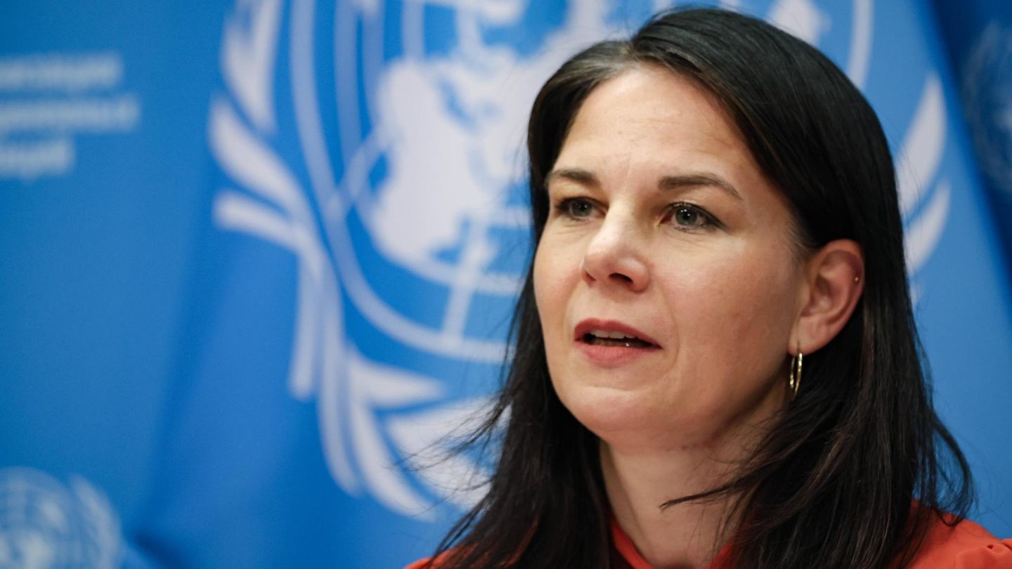 Annalena Baerbock sitzt an einem Tisch und spricht – hinter ihr die hellblau-weiße Flagge der UN