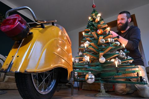 Jan Hofmann schmückt einen Weihnachtsbaum auch mit Weihnachtsbaumkugeln aus Simson-Blinkern. Foto: Martin Schutt/dpa