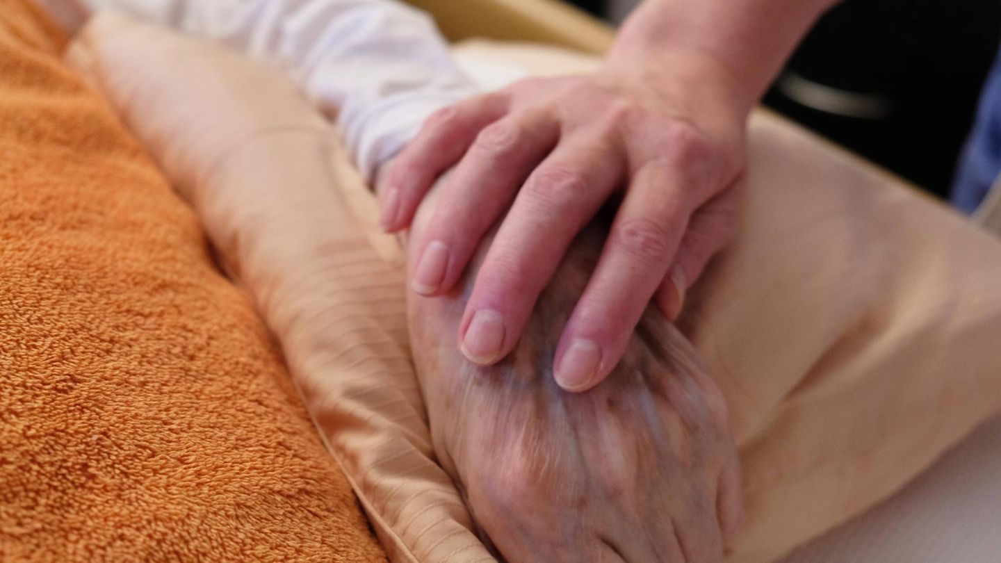 Die Hand eines jungen Menschen liegt auf der eines älteren Menschen