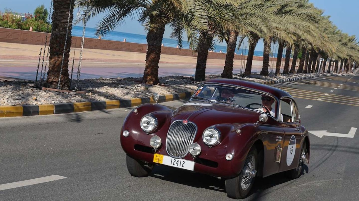 Jaguar XK 120 auf der Straße zwischen Palmen
