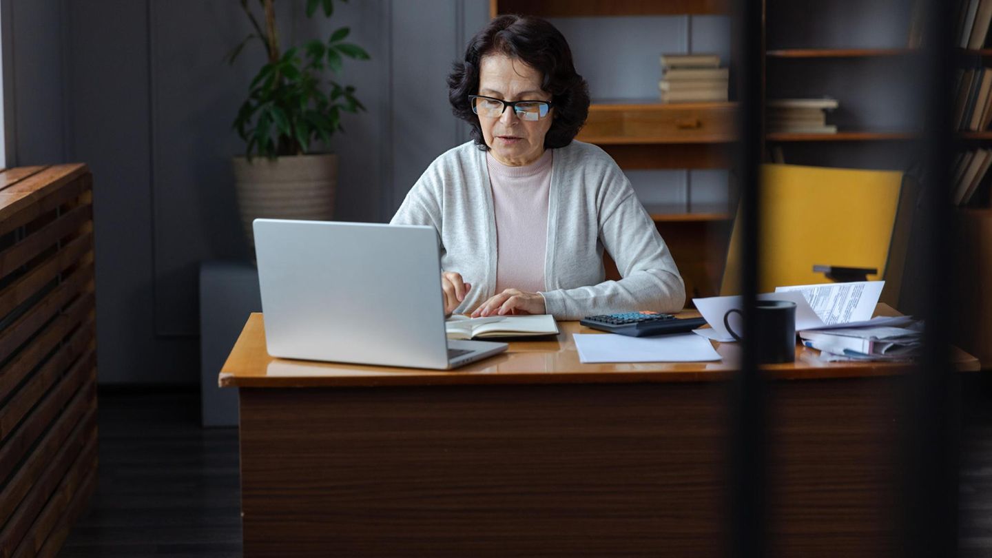 Eine Frau in Rente sitzt an einem Schreibtisch und arbeitet