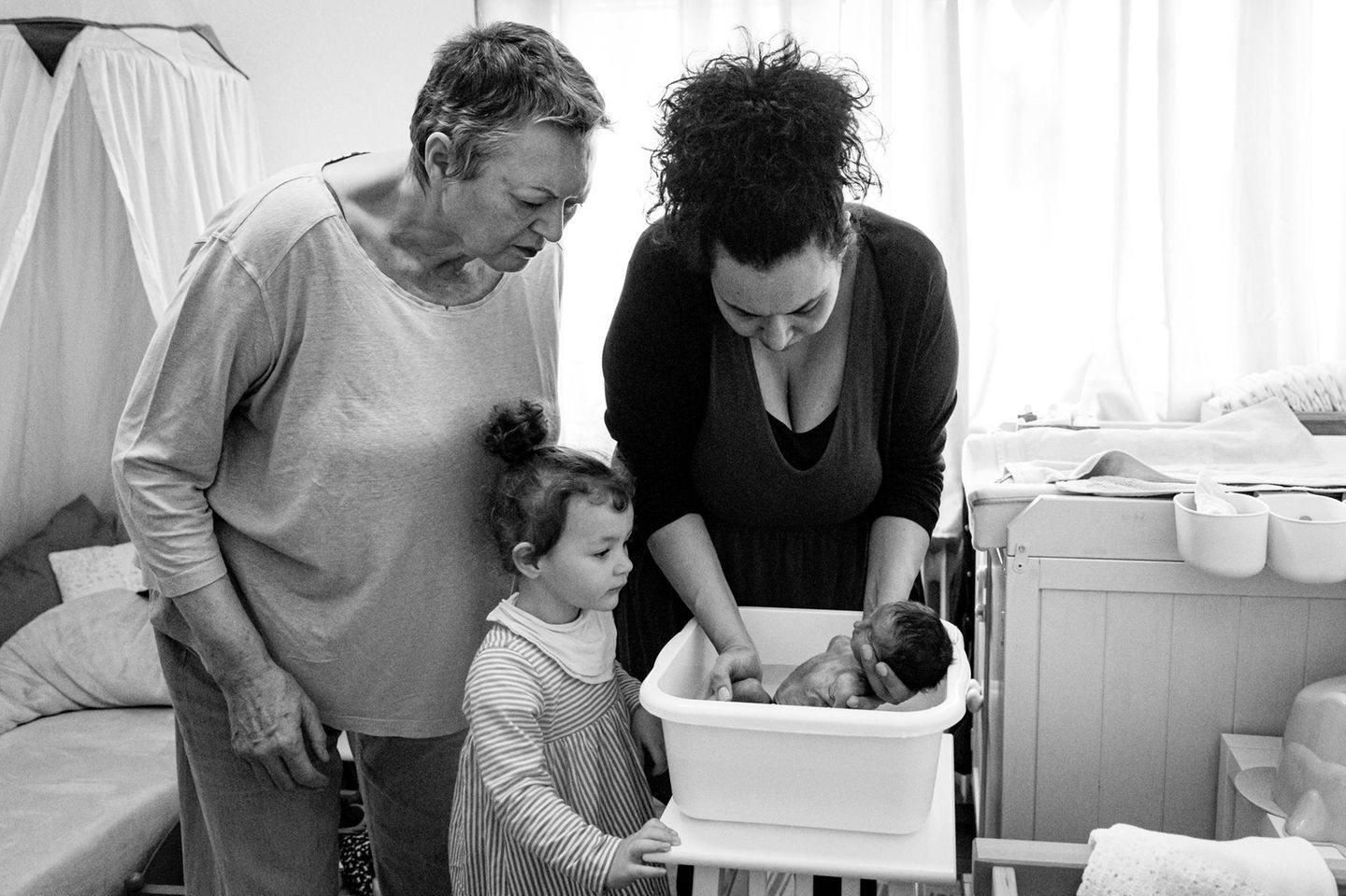 Zwei Frauen und ein Kind, die ein Baby baden