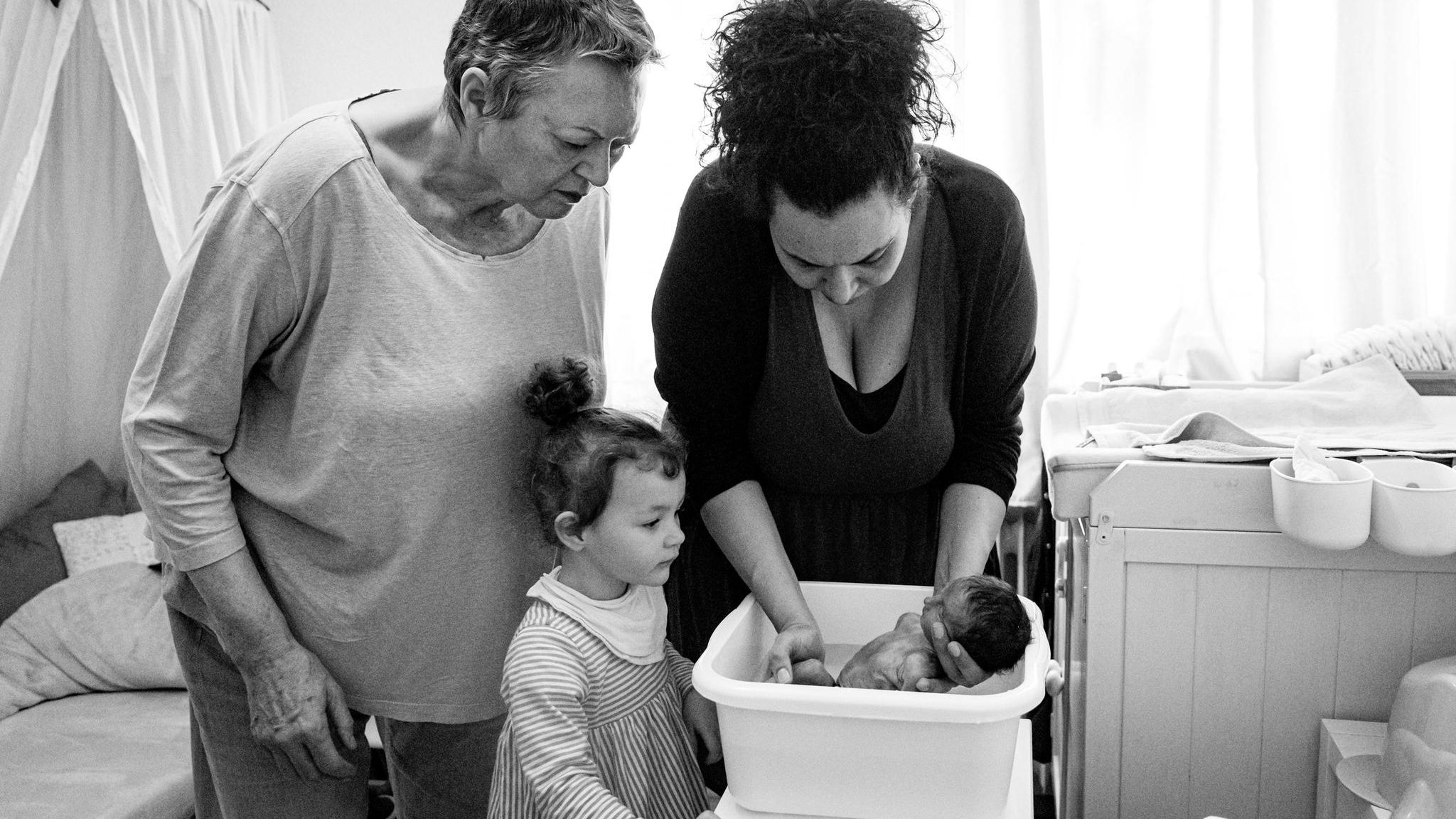 Zwei Frauen und ein Kind, die ein Baby baden