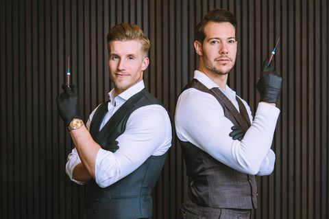 Dr. Rick und Dr. Nick: zwei Männer in Anzügen und Gummihandschuhen halten Spritzen in der Hand