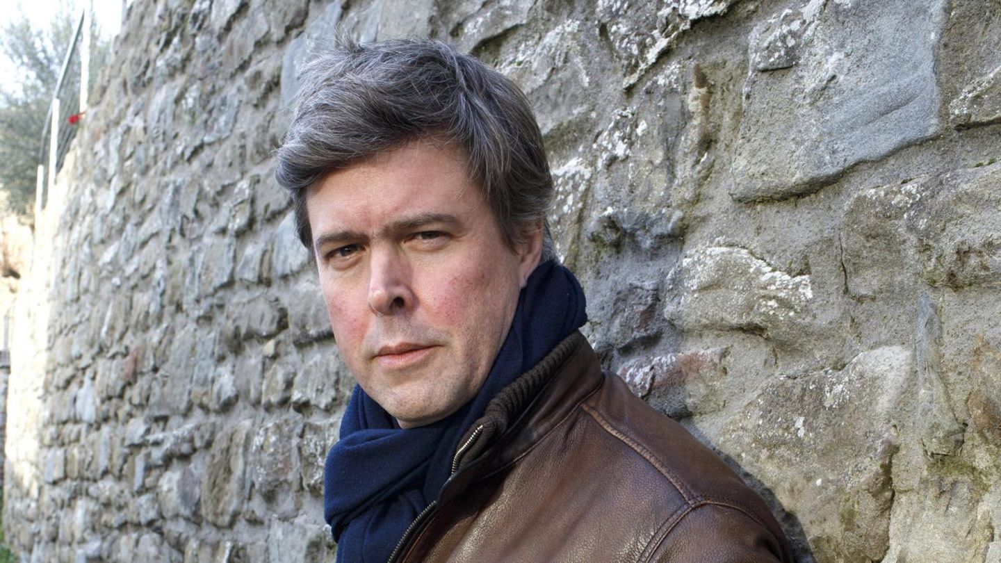 Autor David Szalay lehnt an einer Steinwand