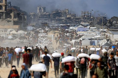 Menschen auf der Flucht mit Packsäcken über den Köpfen