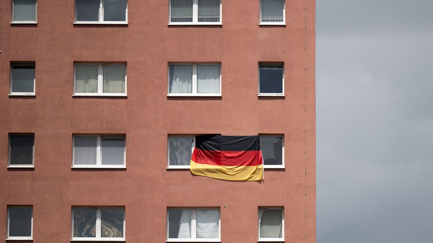 Die Bundesflagge hängt zwischen zwei Fenstern eines Plattenbaus in Halle/Saale. (Archivbild) Foto: Hendrik Schmidt/dpa