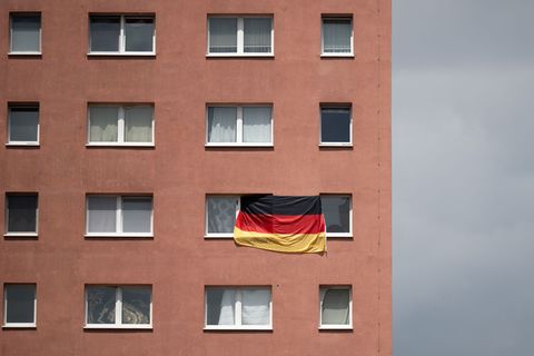 Die Bundesflagge hängt zwischen zwei Fenstern eines Plattenbaus in Halle/Saale. (Archivbild) Foto: Hendrik Schmidt/dpa