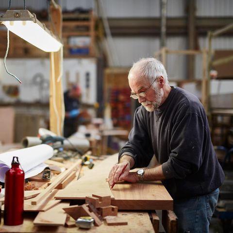 Handwerker in fortgeschrittenem Alter bereitet eine Holzplatte fürs Zuschneiden vor: Rente mit 70 Symbolbild
