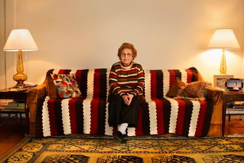 Rente ohne gearbeitet zu haben, Symbolbild: Ältere Frau sitzt auf gemustertem Sofa