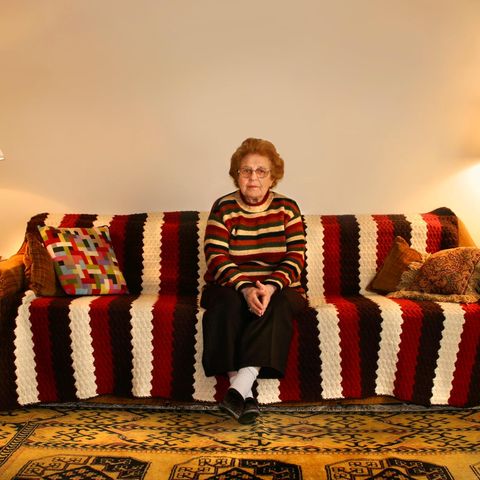 Rente ohne gearbeitet zu haben, Symbolbild: Ältere Frau sitzt auf gemustertem Sofa