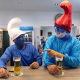 Zwei Männer im Schlumpfkostüm sitzen in einer Bar