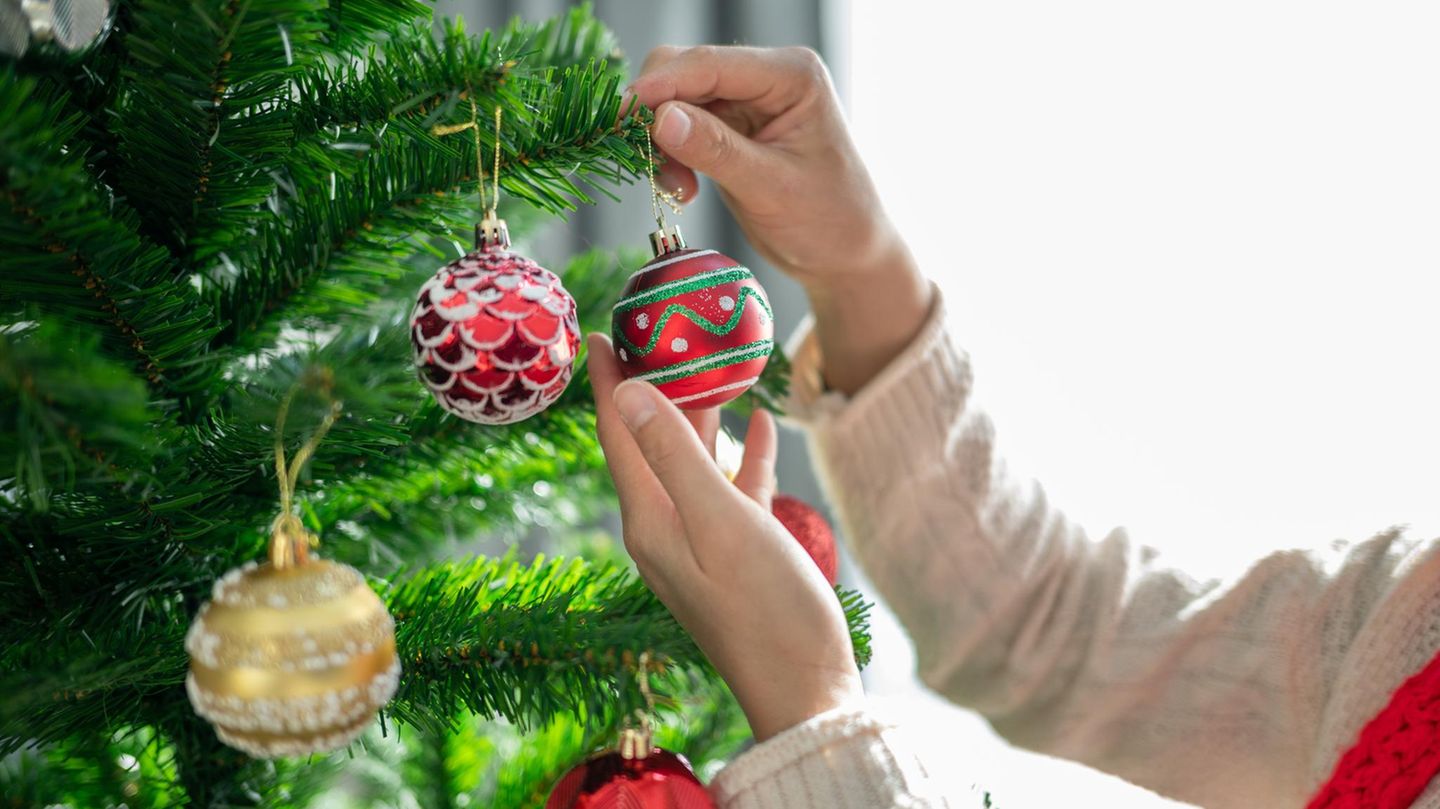 Weihnachtsbaum-Deal: Frau dekoriert künstlichen Baum mit Kugeln