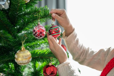 Weihnachtsbaum-Deal: Frau dekoriert künstlichen Baum mit Kugeln