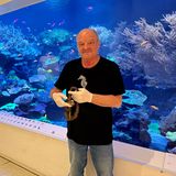 Ein mittelalter Mann in schwarzem T-Shirt hält einen Borstenwurm in den Händen