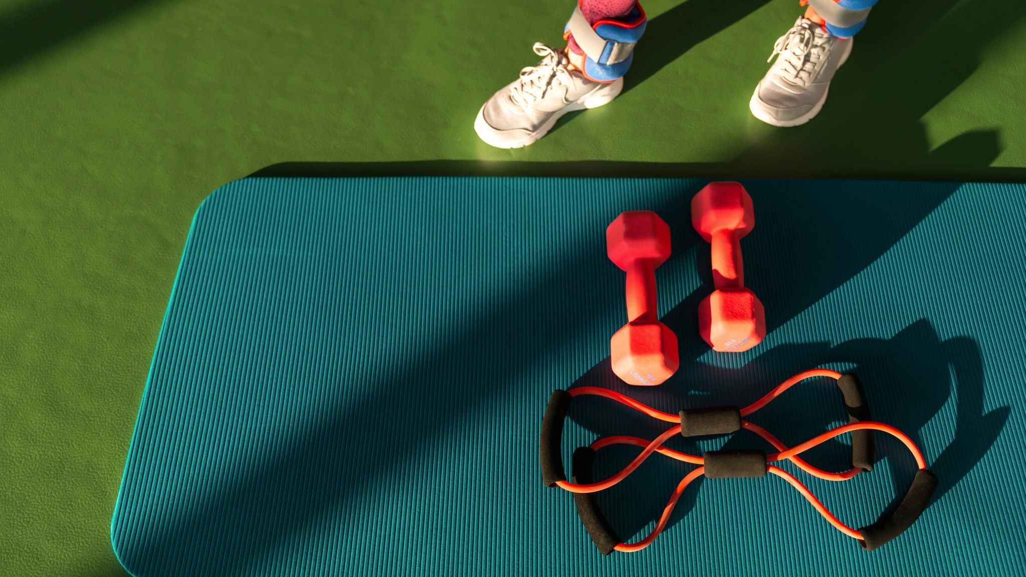 Training für die Muskeln: eine Frau in Sportklamotten steht vor ihrem Sportequipment