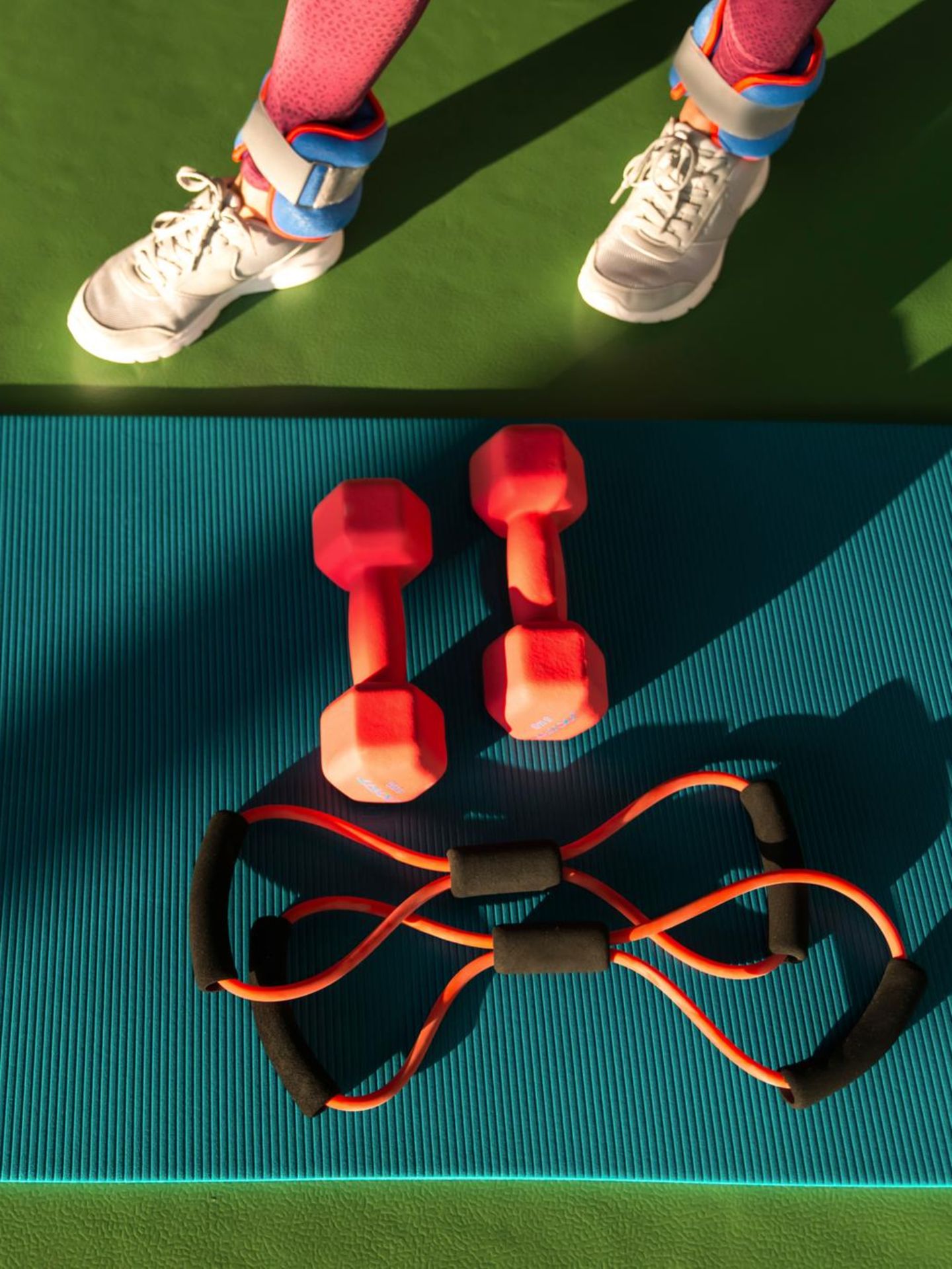 Training für die Muskeln: eine Frau in Sportklamotten steht vor ihrem Sportequipment