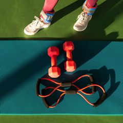 Training für die Muskeln: eine Frau in Sportklamotten steht vor ihrem Sportequipment